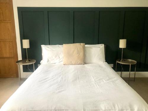 ein großes weißes Bett mit zwei Tischen und zwei Lampen in der Unterkunft Cottage in heart of Perthshire in New Scone