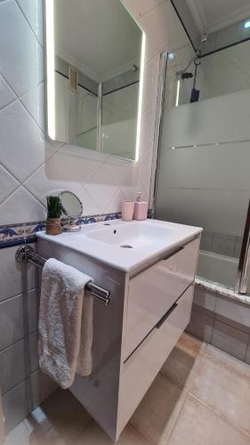 ein Badezimmer mit einem weißen Waschbecken und einem Spiegel in der Unterkunft Villaplaya Fontefría in Boiro