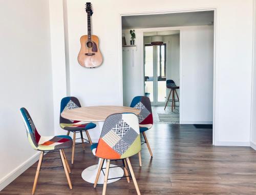 - une table et des chaises dans une pièce avec une guitare dans l'établissement Grand Bleu, Vue sur Lac, Cosy et Chic WIFI Centre ville, Plage, à Istres