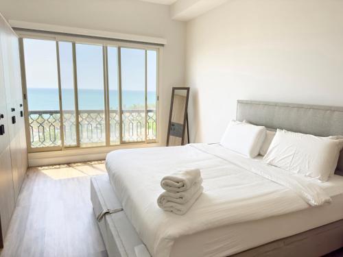 a bedroom with a large white bed with a large window at Bab Al Bahr Residence - Blue Collection Holiday Homes in Ras al Khaimah