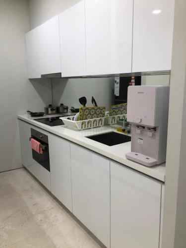 a kitchen with white cabinets and a sink and a microwave at Sky Suites at KLCC by Mitstay in Kuala Lumpur