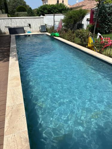 une piscine avec de l'eau bleue dans une cour dans l'établissement A l'ombre des oliviers, à LʼIsle-sur-la-Sorgue