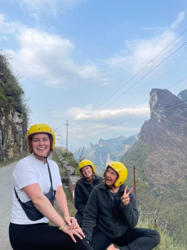 three women wearing yellow helmets sitting on the side of a mountain at Strawberry House , Tour & Motorbikes Rentel in Ha Giang