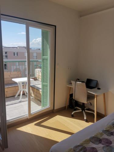 Cet appartement comprend une chambre avec un bureau et un balcon avec une fenêtre. dans l'établissement Juan 3 chambres - terrasses - plage, à Juan-les-Pins