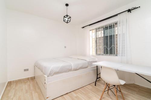 a white bedroom with a bed and a desk at Beths serviced apartments in Ruiru