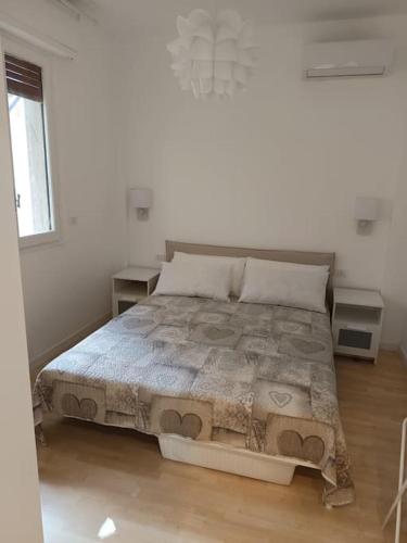 a bedroom with a large bed in a white room at Accogliente Bilocale -parcheggio privato- in Sanremo