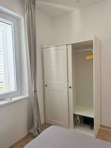 a white cabinet in a bedroom with a window at Apartment Block Two in Šibenik