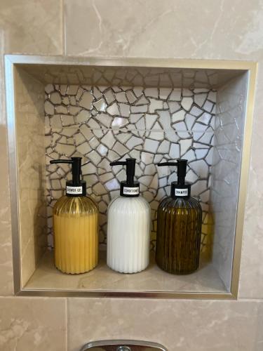 three bottles of soap in a shelf in a bathroom at Villa Ana - Charming Appartments in Belgrade