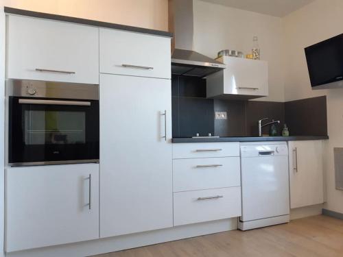 Il comprend une cuisine blanche avec des placards blancs et une télévision. dans l'établissement studio la pierre saint martin refait au gout du jour vue sur la vallée, à La Pierre Saint Martin