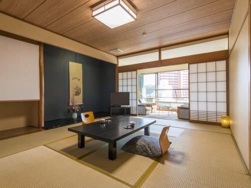 a living room with a table and a chair in it at 伊豆長岡温泉 ホテル茜 in Izunokuni
