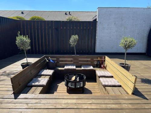 a patio with two benches and two potted trees at Wellness House in Frederikssund