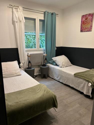 Un dormitorio con dos camas y una ventana. en Chez Muriel, en Porto Vecchio