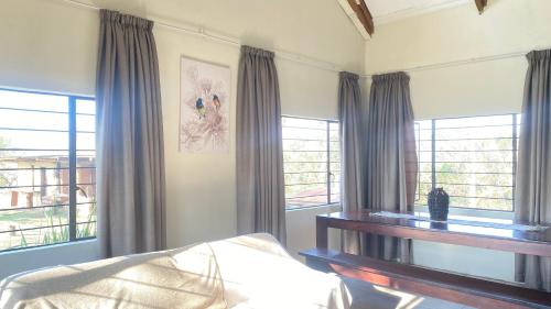 a bedroom with a bed and windows with curtains at Wide Horizons Mountain Retreat in Malkerns