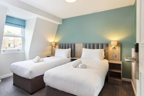 a hotel room with two beds and a window at Prince William Hotel in London