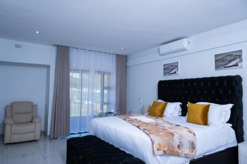 a bedroom with a large bed and a chair at De Lux Villa in Bulawayo