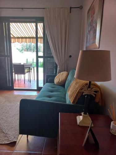 a living room with a blue couch and a lamp at Olhando um Campo de Golf in Islantilla