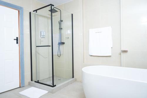 a bathroom with a glass shower and a tub at De Lux Villa in Bulawayo