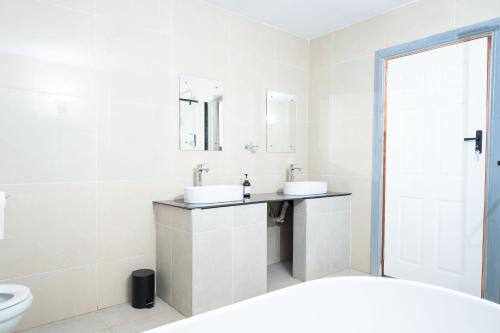 a white bathroom with two sinks and a toilet at De Lux Villa in Bulawayo