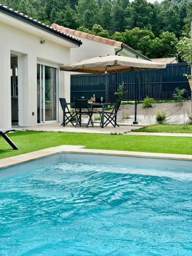 - une piscine dans une cour avec une table et un parasol dans l'établissement Les Villas du Lignon - Votre escapade en Ardèche avec piscine privée, à Pont-de-Labeaume
