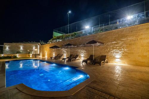 a swimming pool at night with chairs and umbrellas at Amour Relax Hotel in Almirida