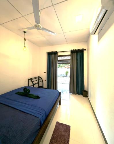 a bedroom with a blue bed and a window at La Breeze in Arugam Bay
