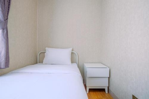 a small bedroom with two beds and a nightstand at Best Deal and Comfortable 2BR Transpark Cibubur Apartment near Mall By Travelio in Depok