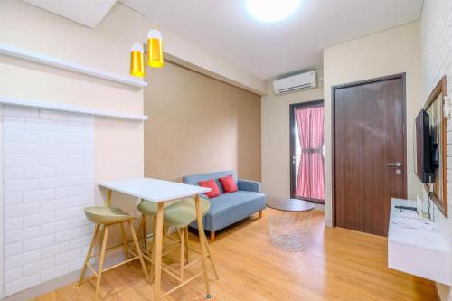 a living room with a blue couch and a table at Best Deal and Comfortable 2BR Transpark Cibubur Apartment near Mall By Travelio in Depok