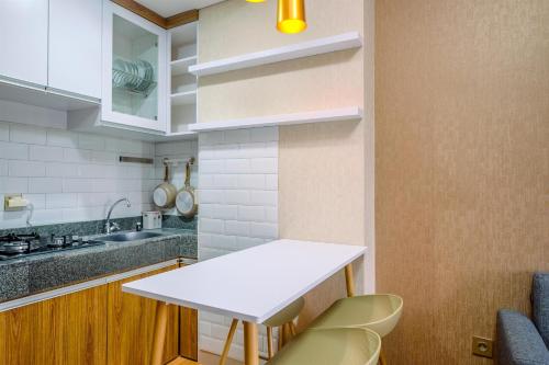 a small kitchen with a white counter and chairs at Best Deal and Comfortable 2BR Transpark Cibubur Apartment near Mall By Travelio in Depok