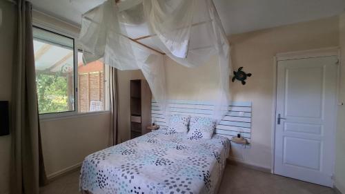 - une chambre avec un lit doté d'une couette blanche et d'une fenêtre dans l'établissement Le Havre du Voyageur - Hibiscus, à Le Moule