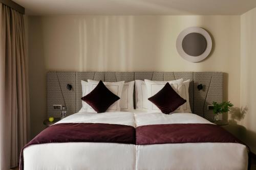 a large bed with red and white sheets and pillows at SCHLOSS Zermatt - CBD & Adaptogenic Spa and Sport Hotel in Zermatt