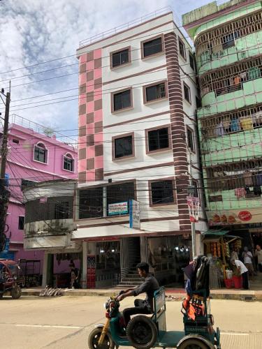a man riding a motorcycle with a cart in front of a building at Hotel Asia in Cox's Bazar