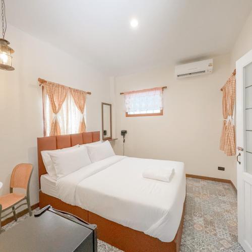 a bedroom with a large white bed and a chair at JB Home Bangkok - Victory monument in Bangkok