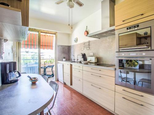 une cuisine avec des armoires en bois et une table à l'intérieur dans l'établissement Apartment L'Hippocampe by Interhome, à Cagnes-sur-Mer