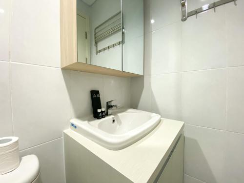 a white bathroom with a sink and a toilet at Great Choice and Comfort Stay 2BR at Patraland Urbano Apartment By Travelio in Bekasi