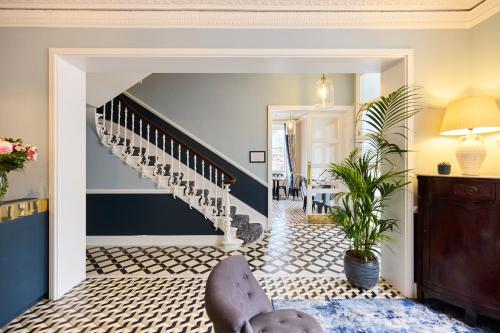 a living room with a staircase and a chair at Prince William Hotel in London