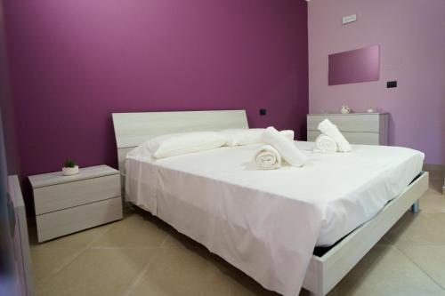 a bedroom with a white bed with a purple wall at Maccuro Luxury Apartment in Vibo Valentia Marina