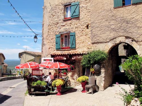 a building with tables and umbrellas in front of it at Holiday Home Maison de Village Les Ormeaux by Interhome in Tourtour
