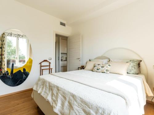 a bedroom with a large white bed with a round mirror at Apartment Citrus Garden by Interhome in Cisano sul Neva