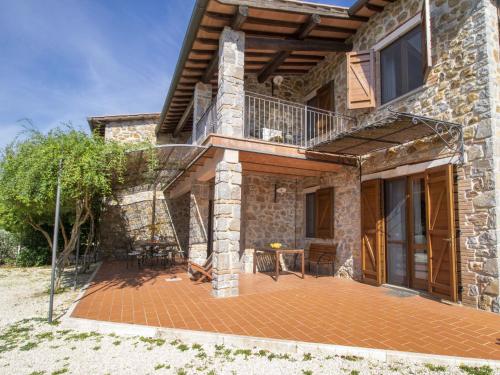 a stone house with a patio and a balcony at Villa La Gattaiola Piccola by Interhome in Montemerano
