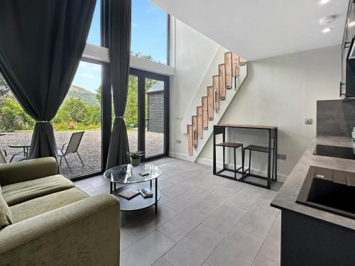 a living room with a couch and a table at Aos Sí - Wellness - Jacuzzi - Lodges in Ballachulish