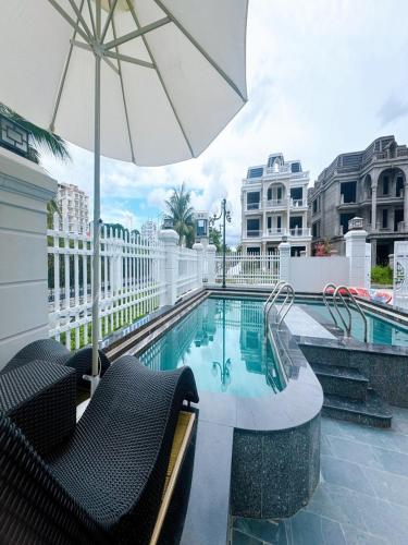 a pool with two chairs and an umbrella and a swimming pool at Villa 13 phòng ngủ vip - Đầy đủ tiện nghi - Bể bơi riêng - Bàn Bi a in Ha Long