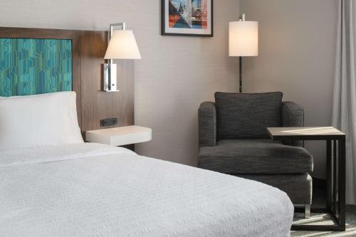 a hotel room with a bed and a chair at Hampton Inn and Suites Seattle - Airport / 28th Avenue in SeaTac