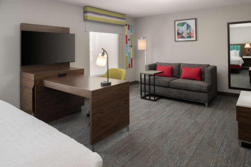 a hotel room with a bed and a desk with a television at Hampton Inn and Suites Seattle - Airport / 28th Avenue in SeaTac