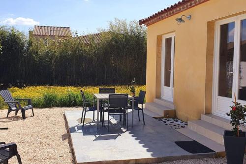 a patio with a table and chairs next to a house at Charmant appartement au calme situé en Camargue in Saint-Laurent-dʼAigouze