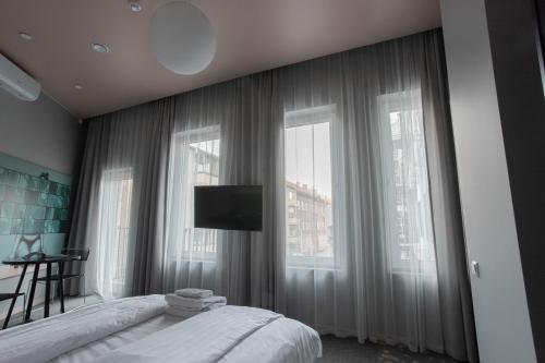 a bedroom with a bed and a tv and windows at Resume apartments in Kaunas