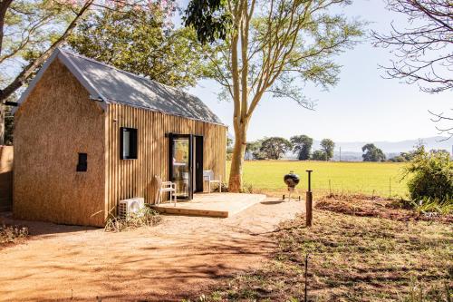 a small wooden house in a field with a tree at Modern Cabin in Malkerns in Malkerns