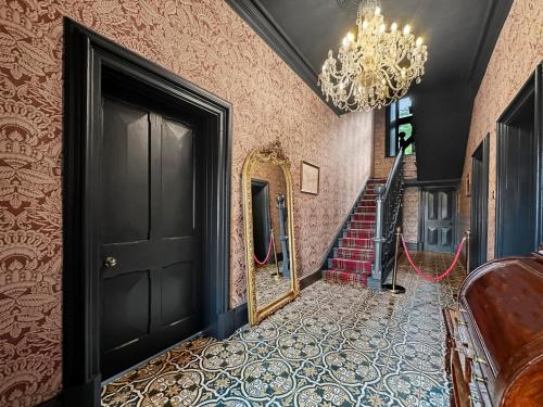 a hallway with a black door and a chandelier at St John's Old Rectory in Glencoe