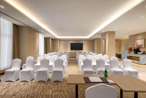 a conference room with white chairs and a screen at Ramada by Wyndham Riyadh King Fahd Road in Riyadh