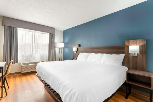 a large white bed in a room with a blue wall at Suburban Studios LaVale - Cumberland in La Vale