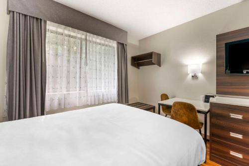 a hotel room with a bed and a desk and a window at Suburban Studios LaVale - Cumberland in La Vale